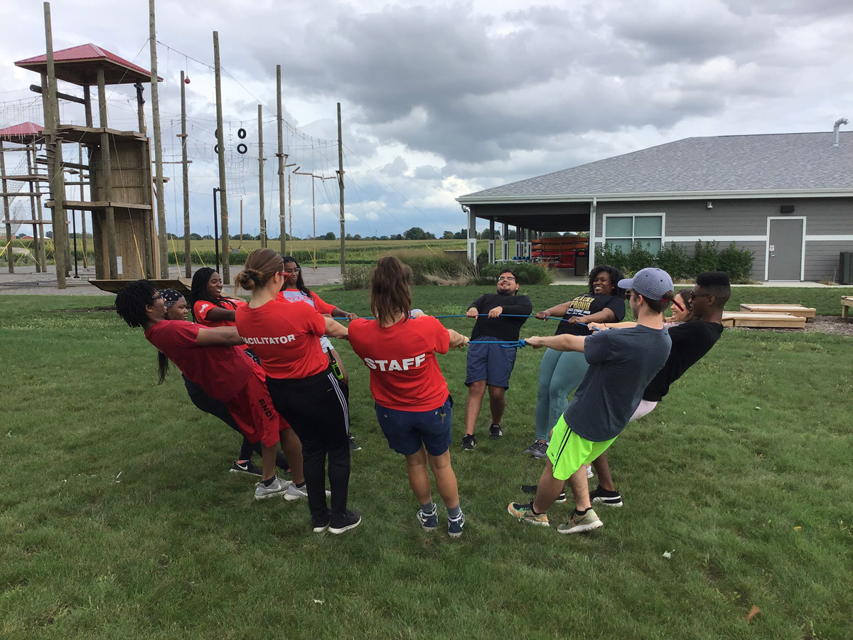 Group of students posing with the High Ropes on the background