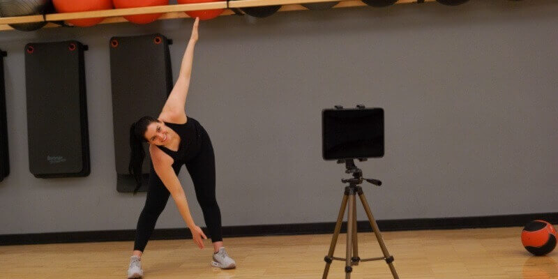A Campus Recreation employee leads a virtual exercise class through an iPad.